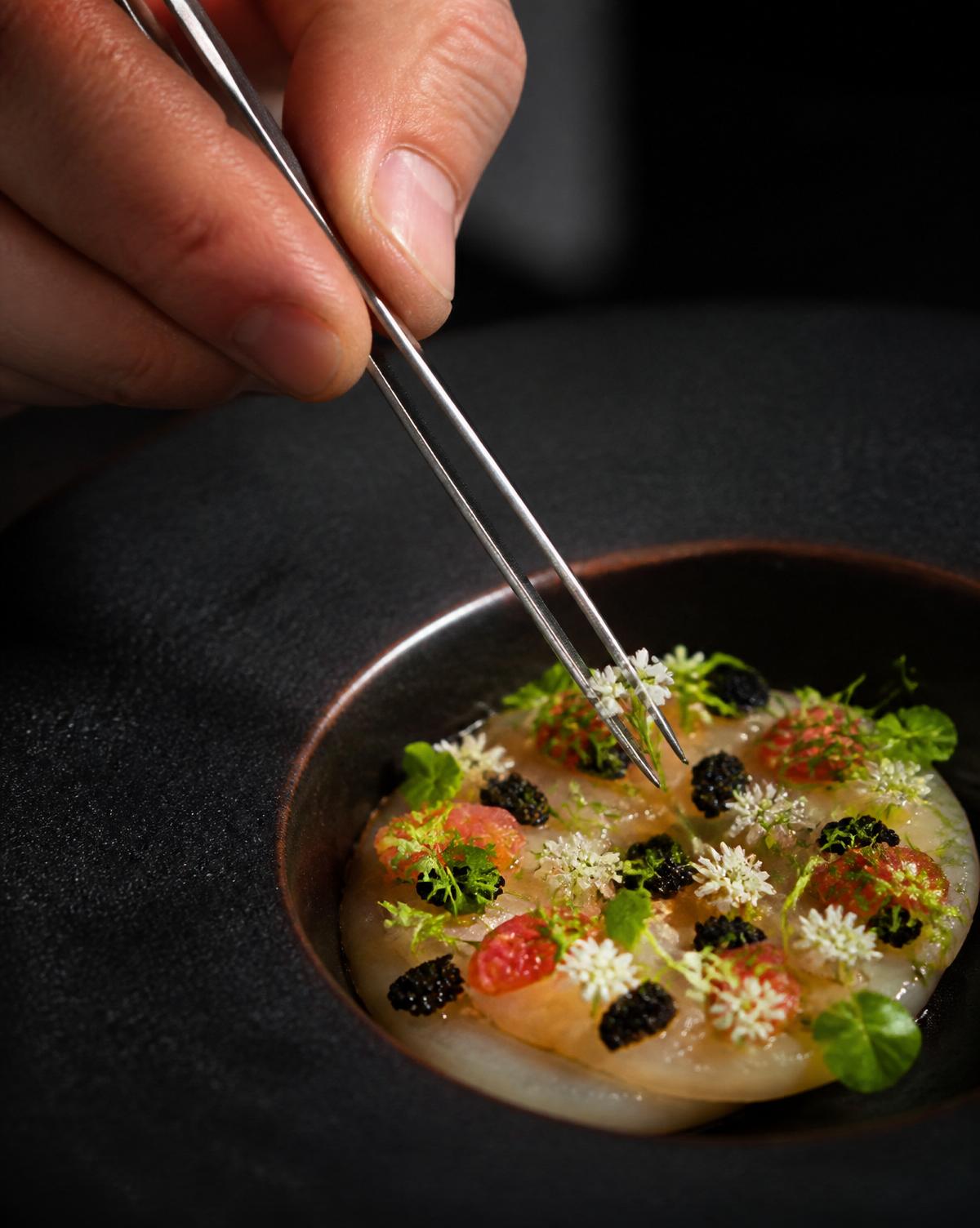 Final dish being plated by the chef.